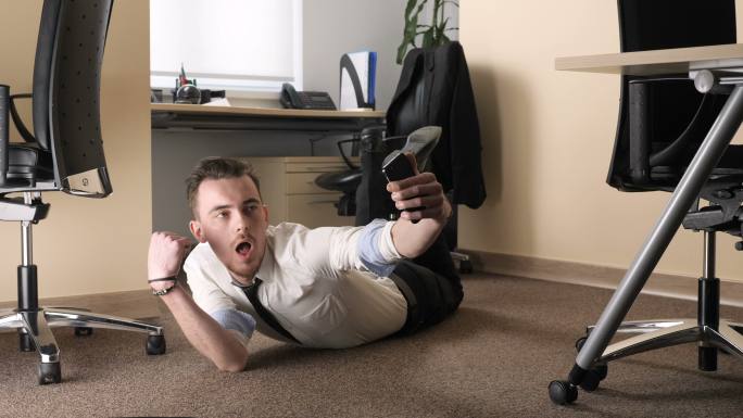 年轻人躺在办公室中央的地板上自拍。