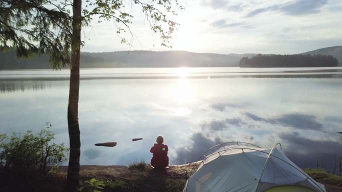 挪威湖边森林里的女人和帐篷