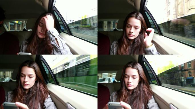 坐在汽车后座玩手机的年轻女子。