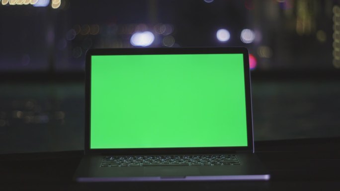屋顶游泳池旁绿色屏幕的笔记本电脑