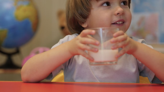 小男孩微笑着，早餐喝牛奶。