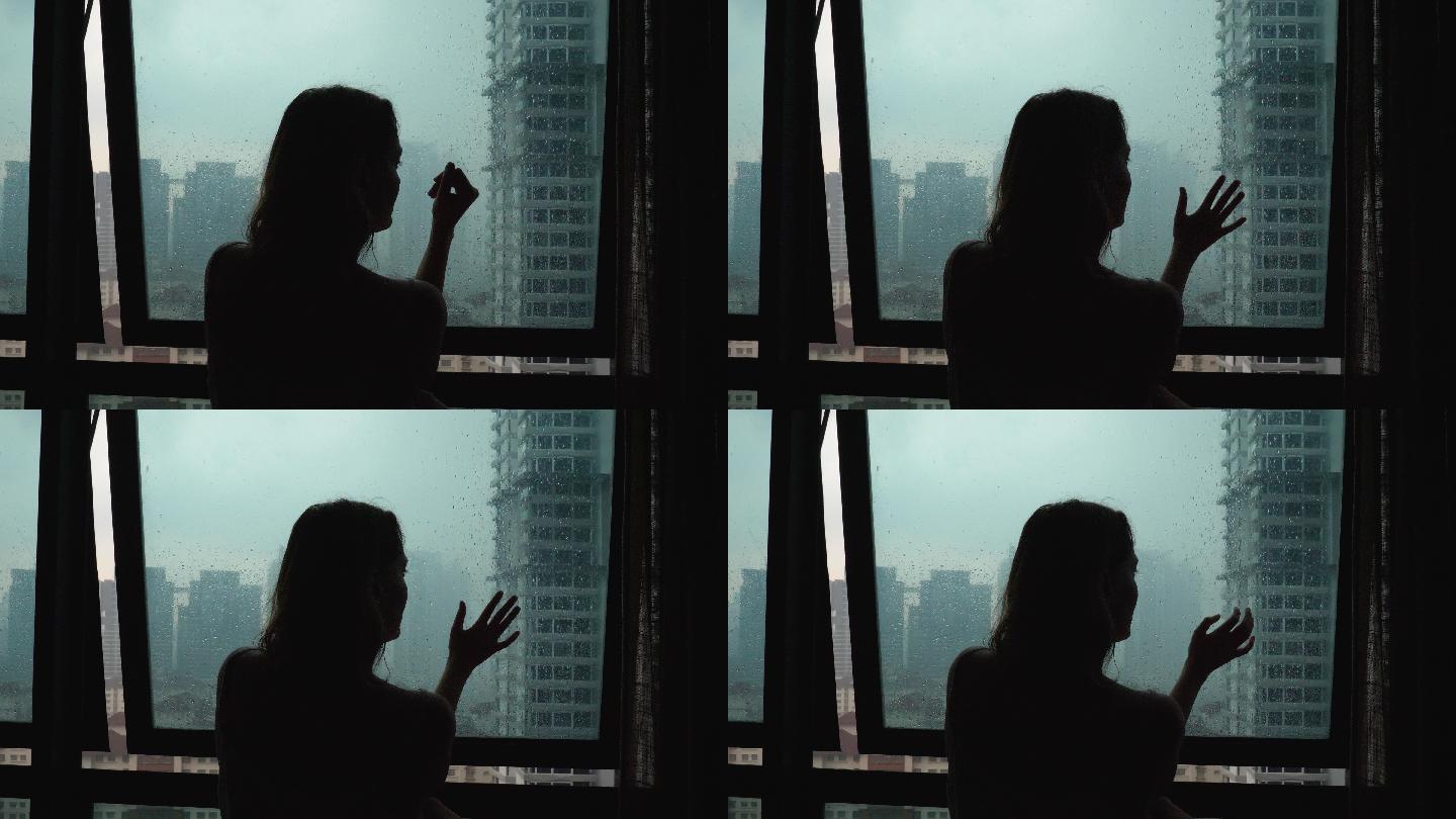 悲伤孤独的女人在雨天触摸玻璃窗
