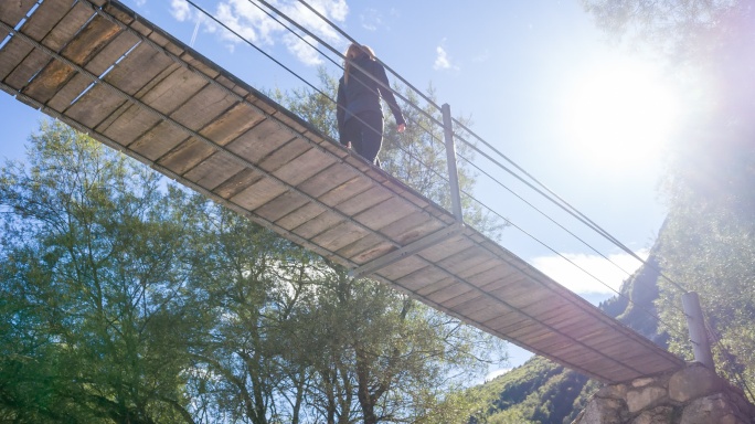 走在木制吊桥上的年轻女子