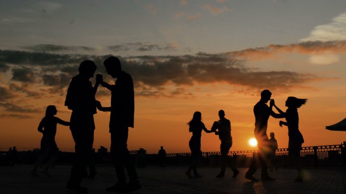 夕阳下，人们在城市堤岸上学习跳舞