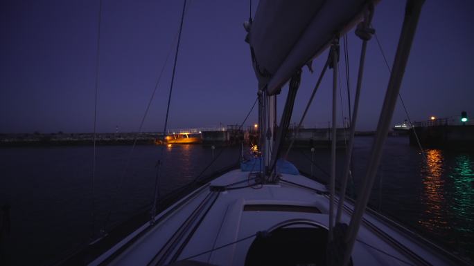 在夜间航行通过港口的帆船