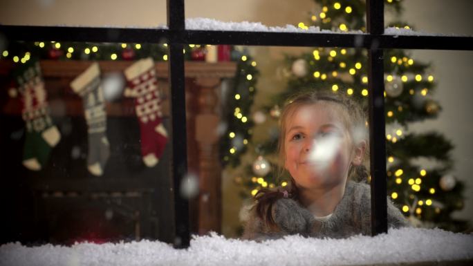 圣诞节时，小女孩凝视着窗外飘落的雪