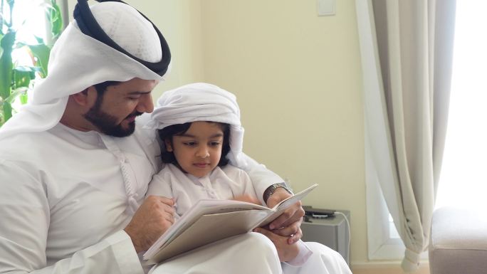 阿拉伯父子在家看书做作业