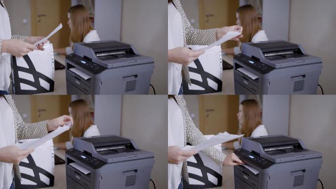 办公室里的一位女士正在从打印机上取文件