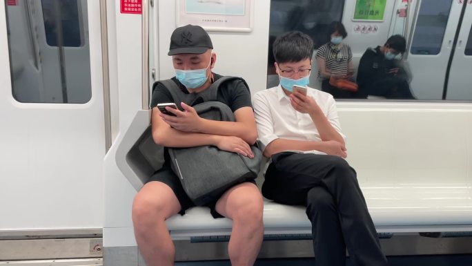坐地铁在车厢中看手机的人