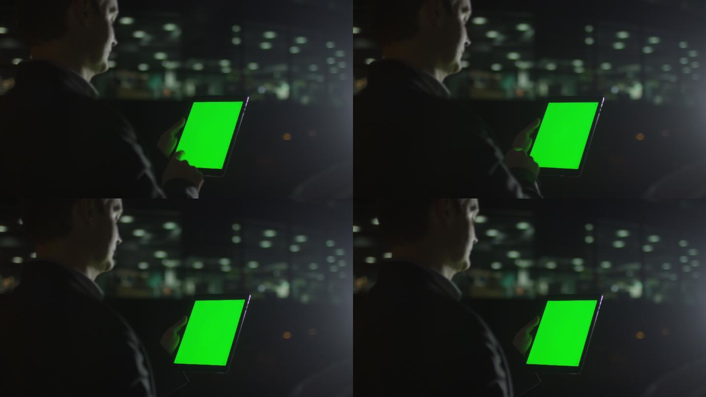 商人在晚上使用绿色屏幕的平板电脑