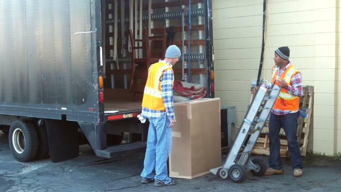 两个工人把大箱子装上运货卡车