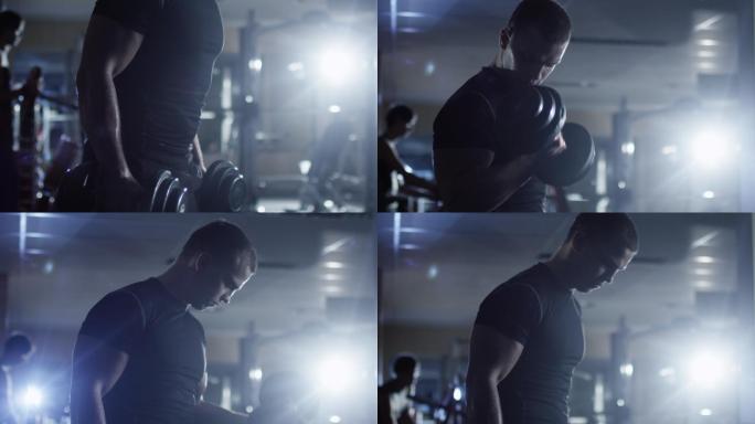 男人在黑暗的健身房做哑铃卷曲运动。