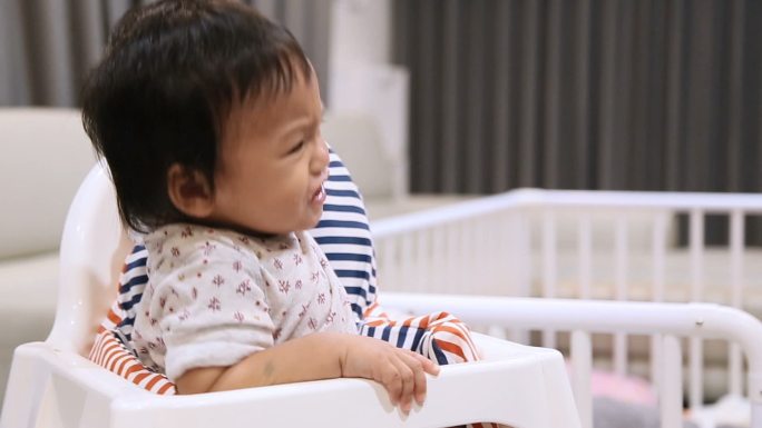 哭闹的婴儿在儿童椅上吃东西