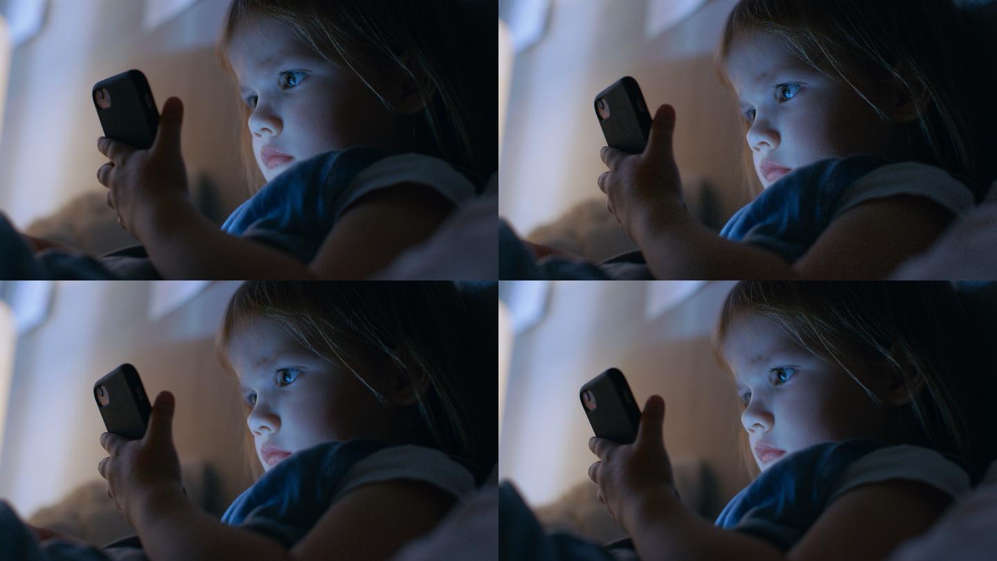 可爱的小女孩用智能手机看动画片