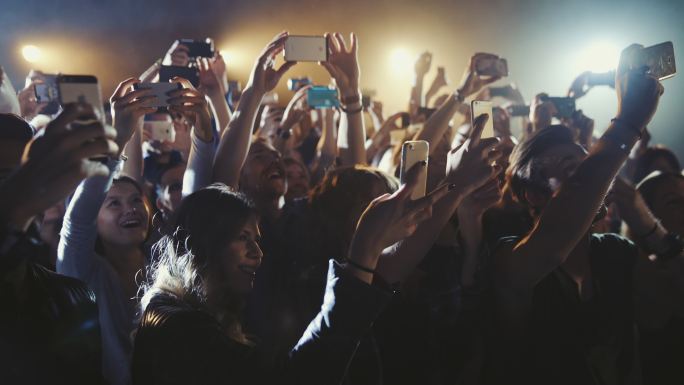 人们在音乐会上用智能手机拍摄和拍照。