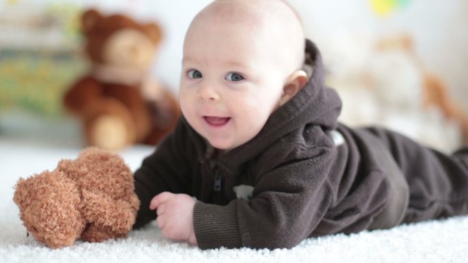 小男婴在家里玩着柔软的泰迪熊玩具