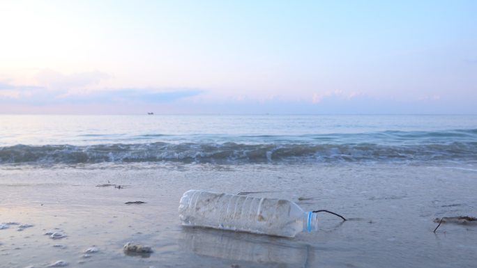 海滩上的塑料瓶捡垃圾饮料瓶再利用海边塑料