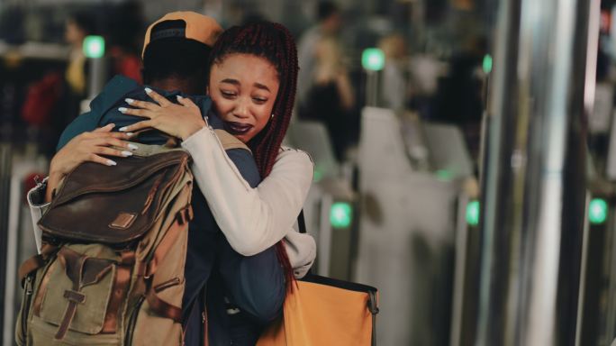 一对年轻夫妇在机场欢送时拥抱哭泣
