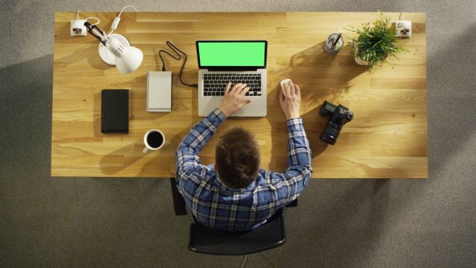 一位男人在笔记本电脑上用绿色屏幕处理照片