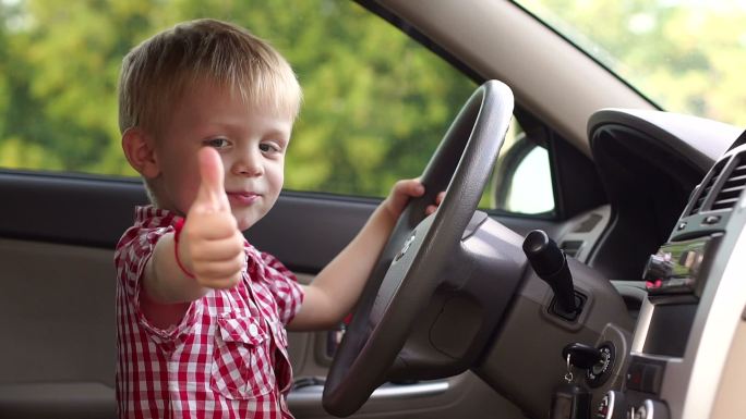 一个快乐男孩坐在汽车里转动方向盘
