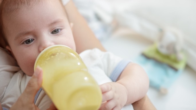 男婴在妈妈怀里用奶瓶喝奶