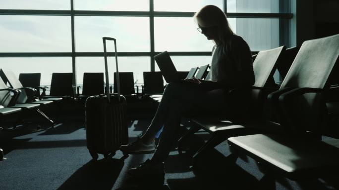 在机场候机楼用笔记本电脑工作的女商人