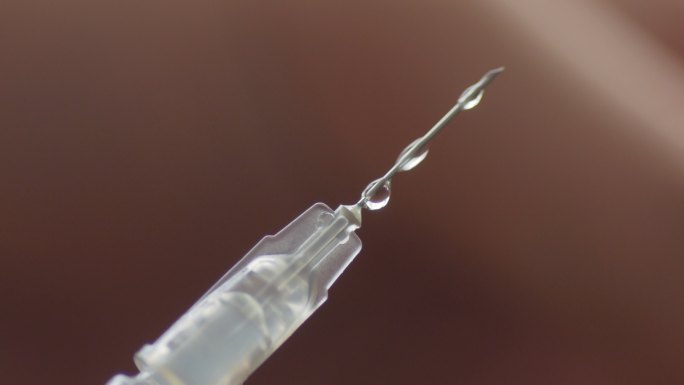 注射器和液体疫苗滴落的特写镜头