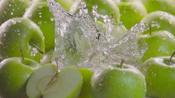 青苹果掉进水里，苹果间溅起水花。