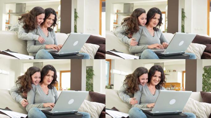 母亲和女儿在客厅玩笔记本电脑的情景。
