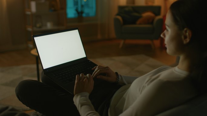 女子在沙发上使用白色模拟屏幕笔记本电脑