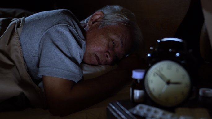 一个沮丧的老人躺在床上失眠睡不着觉