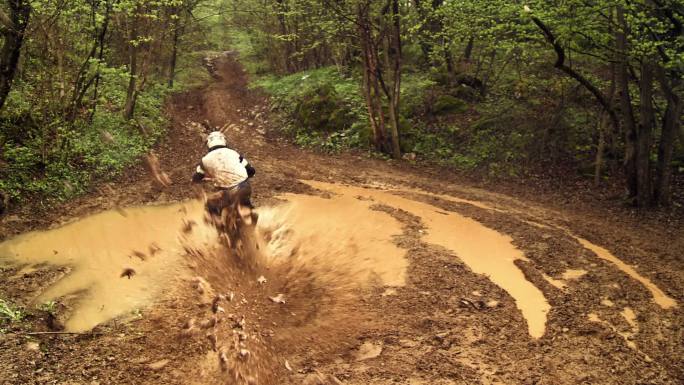 越野摩托车手在泥泞的森林小道上骑车