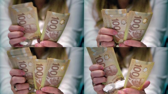 一个女人数着100张加拿大钞票的画面