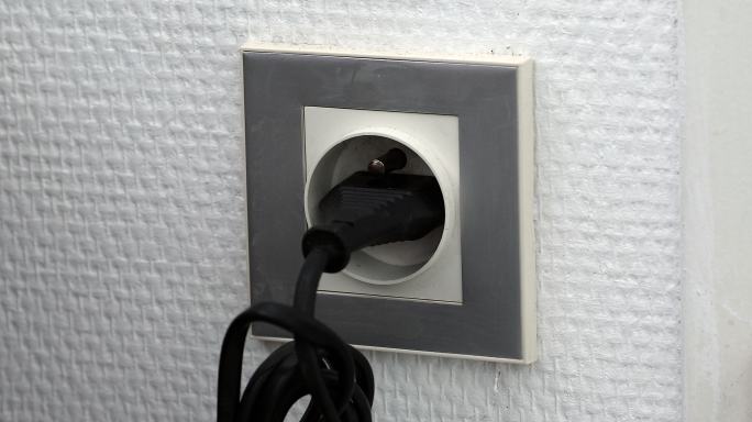 把许多不同的电源插头插入墙上的插座