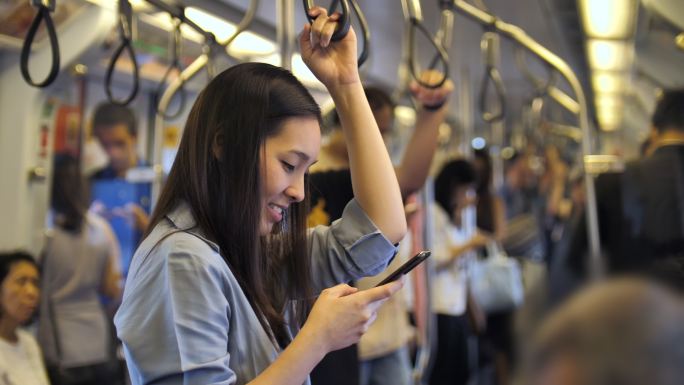 年轻女子在地铁玩手机