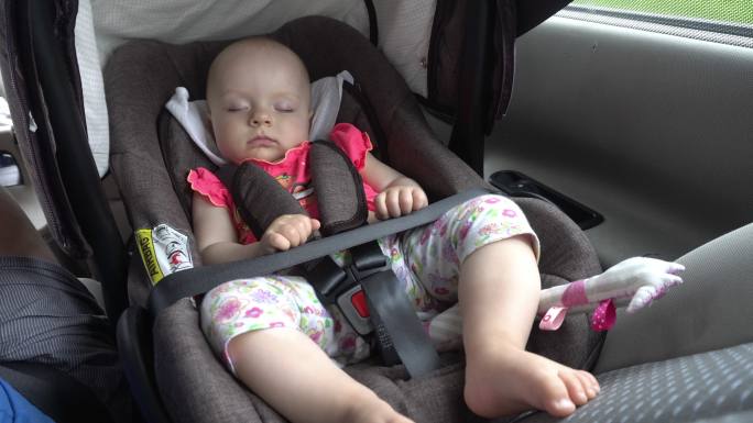 睡在儿童汽车座椅上的女婴