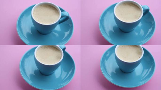 在旋转的粉红色盘子上放有咖啡的蓝色杯子