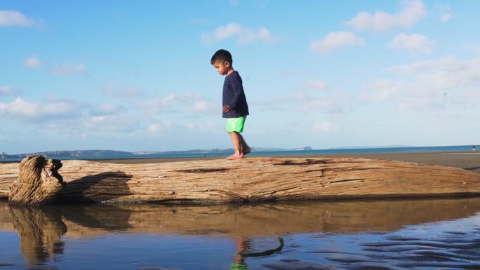 小朋友在沙滩上的木头上行走。