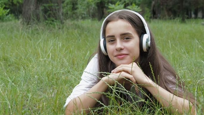 草地上的女孩听音乐。