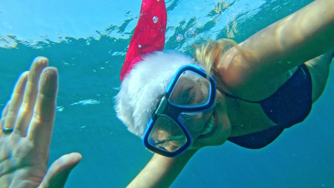 戴着圣诞帽在海里游泳的女人