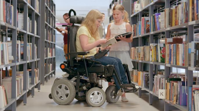 一个女孩把一本书递给坐在轮椅上的女人