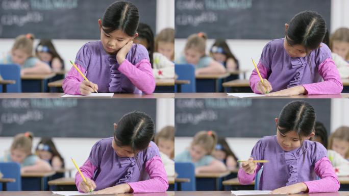 一个小女孩在教室里用铅笔在纸上写字。
