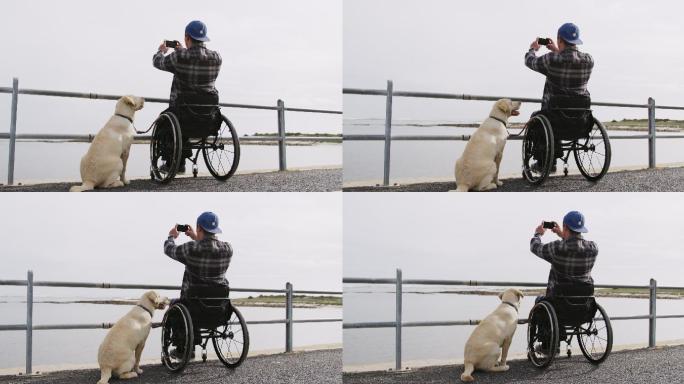 坐在轮椅上的人和他的狗在拍大海的照片
