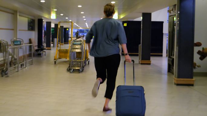 赶路的女人拿着手提箱在机场跑