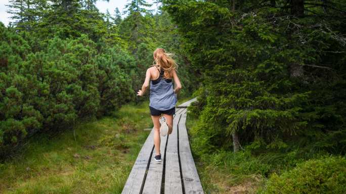 在森林小径上跑步穿过树林的女人