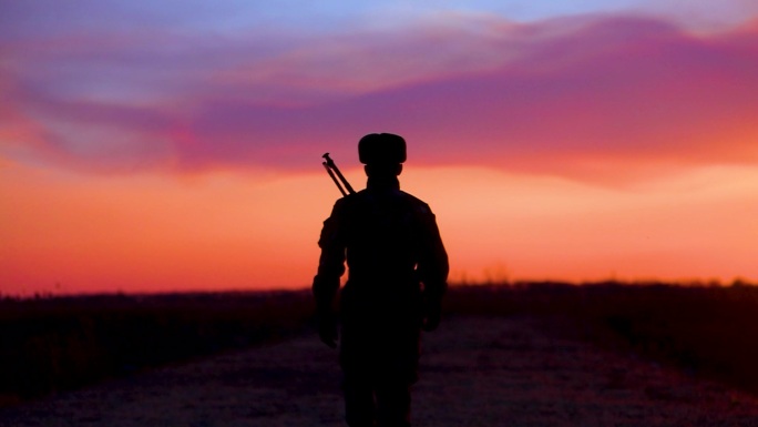 夕阳下士兵步行军人背枪走路剪影空镜