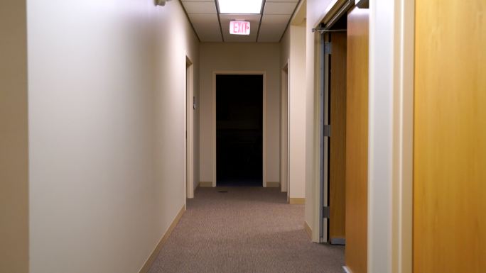 稳定的镜头沿着走廊移动，进入黑暗的房间