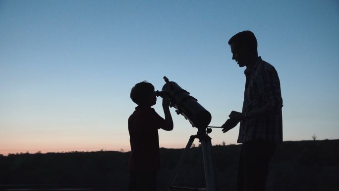 男人和男孩用望远镜观望天空