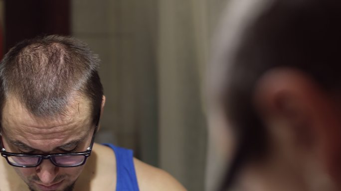 一个男人用剃须刀剃光头上的头发。