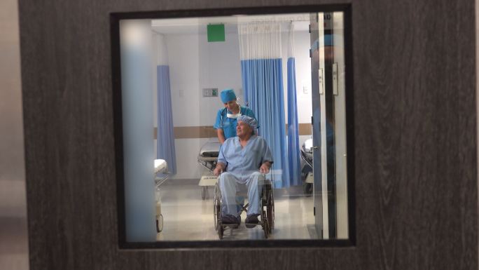 女护士推着轮椅上的老年病人去手术